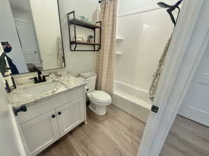 Full bath with vanity, light wood-style flooring, and shower / bathtub combination with curtain