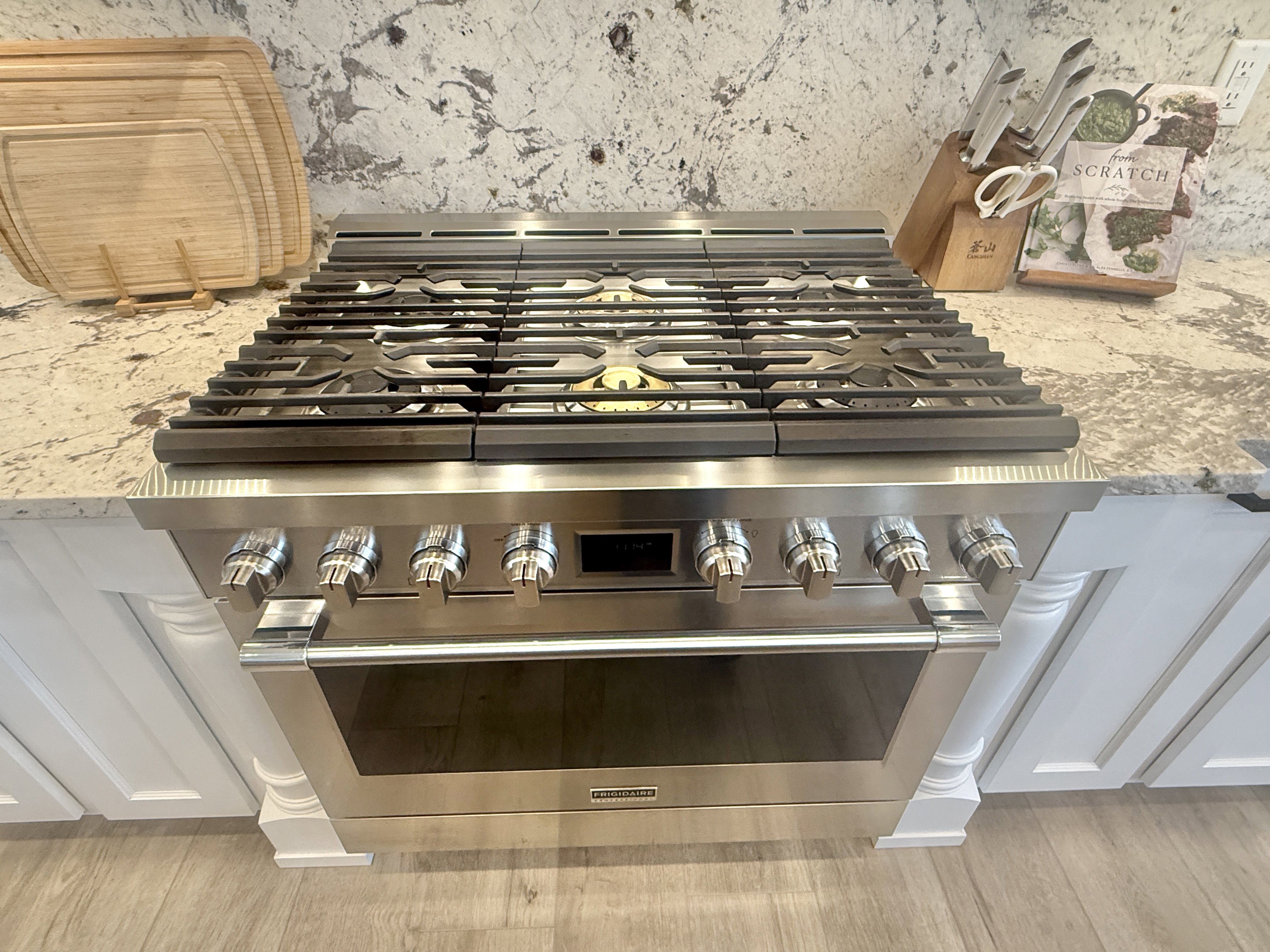 Kitchen view of light stone counters and high end stainless steel range oven