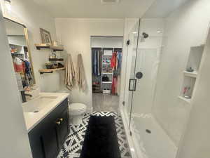 Full bath with a spacious closet, vanity, a shower stall, and light tile patterned floors