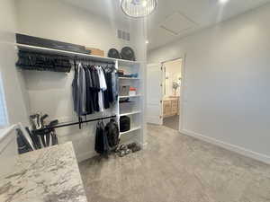 Walk in closet featuring attic access and light carpet