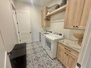 Laundry area with cabinet space, independent washer and dryer, and light tile patterned floors