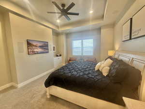 Bedroom featuring light colored carpet, ceiling fan, a tray ceiling, and recessed lighting