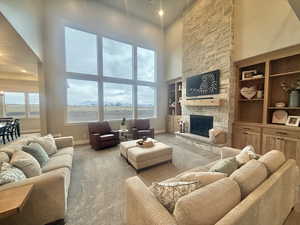 Living room with a high ceiling, a fireplace, recessed lighting, healthy amount of natural light, and carpet flooring