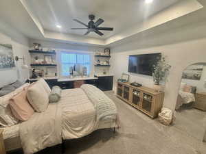 Bedroom with a tray ceiling, light carpet, ceiling fan, and recessed lighting
