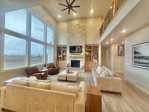 Living area featuring a high ceiling, a fireplace, light wood-style floors, built in shelves, and recessed lighting
