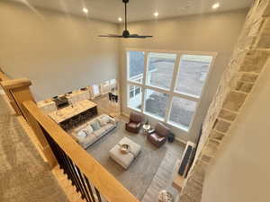 Living area with a high ceiling, ceiling fan, wood finished floors, and recessed lighting