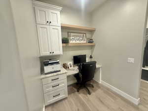 Office space featuring built in study area and light wood-style flooring