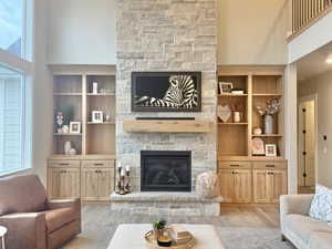 Living area with a high ceiling, a fireplace, and wood finished floors