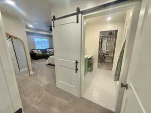 Corridor with a barn door, light colored carpet, and recessed lighting