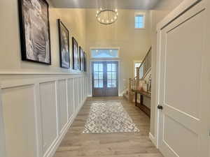 Doorway to outside featuring french doors, wood finished floors, hanging lights, and a high ceiling