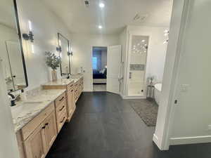 Ensuite bathroom with double vanity, a stall shower, a soaking tub, dark tile patterned flooring, and recessed lighting