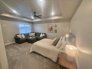 Carpeted bedroom featuring a tray ceiling, a ceiling fan, and recessed lighting
