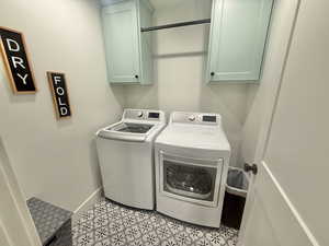 Laundry area featuring washing machine and dryer, cabinet space, and light tile patterned floors