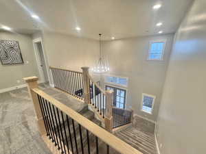 Staircase with carpet flooring and hanging lights