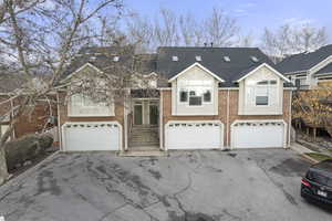 View of front of house with brick siding, a garage, driveway, roof with shingles, and french doors