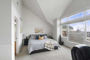 Primary Bedroom with light colored carpet and vaulted ceiling