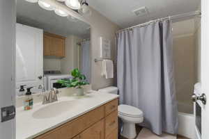 Bathroom with vanity, washer / clothes dryer, and shower / bath combo