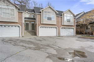 View of front of home with brick siding, a garage, and driveway
