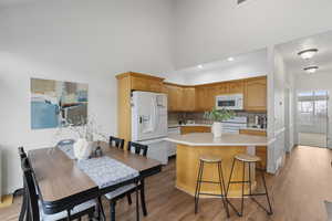 Kitchen with light countertops, white appliances, a center island, backsplash, and light wood-type flooring