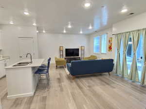 Living area with light wood finished floors and recessed lighting