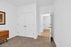 Unfurnished bedroom featuring light carpet and a closet