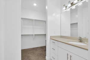 Full bath featuring a walk in closet, vanity, and carpet