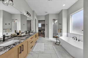 Bathroom featuring a tile shower, a freestanding tub, double vanity, light marble finish flooring, and healthy amount of natural light