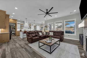 Living area with a ceiling fan, wood finished floors, a fireplace, and recessed lighting