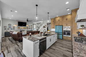 Kitchen with dark stone countertops, open floor plan, stainless steel appliances, ceiling fan, and a fireplace