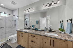 Bathroom with double vanity and a marble finish shower