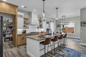 Kitchen featuring a barn door, dark stone counters, a breakfast bar, light wood-style floors, and two tone cabinets