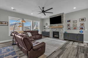 Living area with ceiling fan, wood finished floors, a fireplace, and recessed lighting