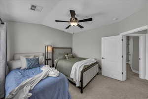 Carpeted bedroom featuring a ceiling fan and vaulted ceiling