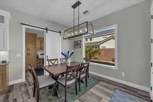 Dining space featuring a barn door, light wood-type flooring, and a chandelier