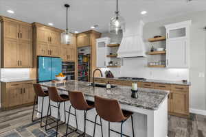 Two tone kitchen with dark stone countertops, a breakfast bar area, light wood-type flooring, and two tone cabinets