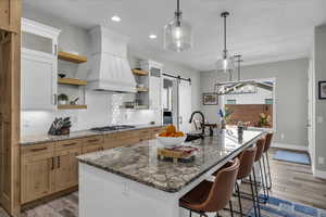 Two tone kitchen featuring a barn door, dark stone countertops, two tone cabinets, a breakfast bar area, and a kitchen island with sink