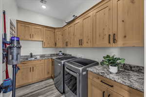 Laundry area with washing machine and dryer, cabinet space, and light wood-style floors