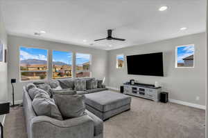 Carpeted living area featuring ceiling fan and recessed lighting
