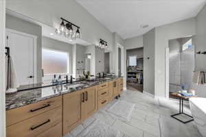 Bathroom featuring double vanity, a soaking tub, light marble finish flooring, walk in shower, and a walk in closet