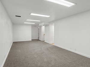 Empty room with light colored carpet and baseboards
