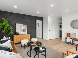 Living area with recessed lighting, a decorative wall, light wood-style flooring, and an accent wall
