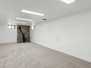 Basement featuring light carpet and a wood stove