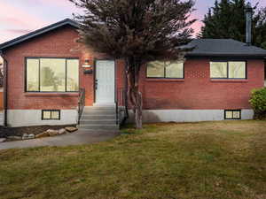 View of front of house featuring brick siding and a lawn