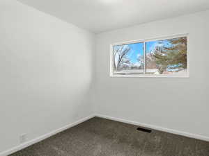 Empty room with baseboards and dark colored carpet