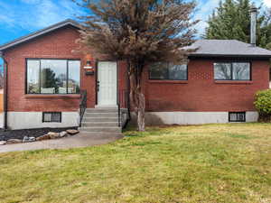 View of front of property with brick siding, a front lawn, and entry steps