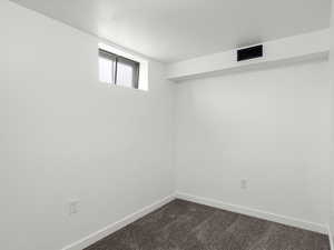 Basement with baseboards and dark carpet