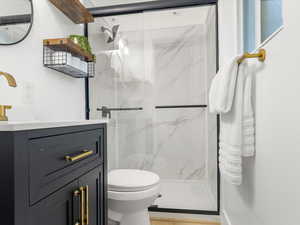 Full bath featuring a marble finish shower and vanity