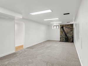 Basement featuring light colored carpet and a wood stove