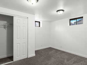 Unfurnished bedroom featuring dark carpet and a closet