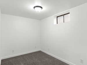 Unfurnished room featuring baseboards and dark colored carpet